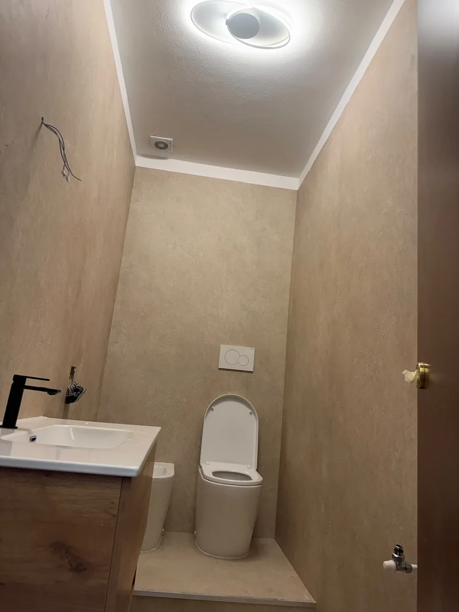 Bagno chiaro con mobile in legno e sanitari bianchi