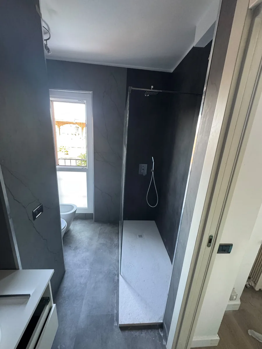 Bagno grigio con doccia in muratura e piatto a filo pavimento