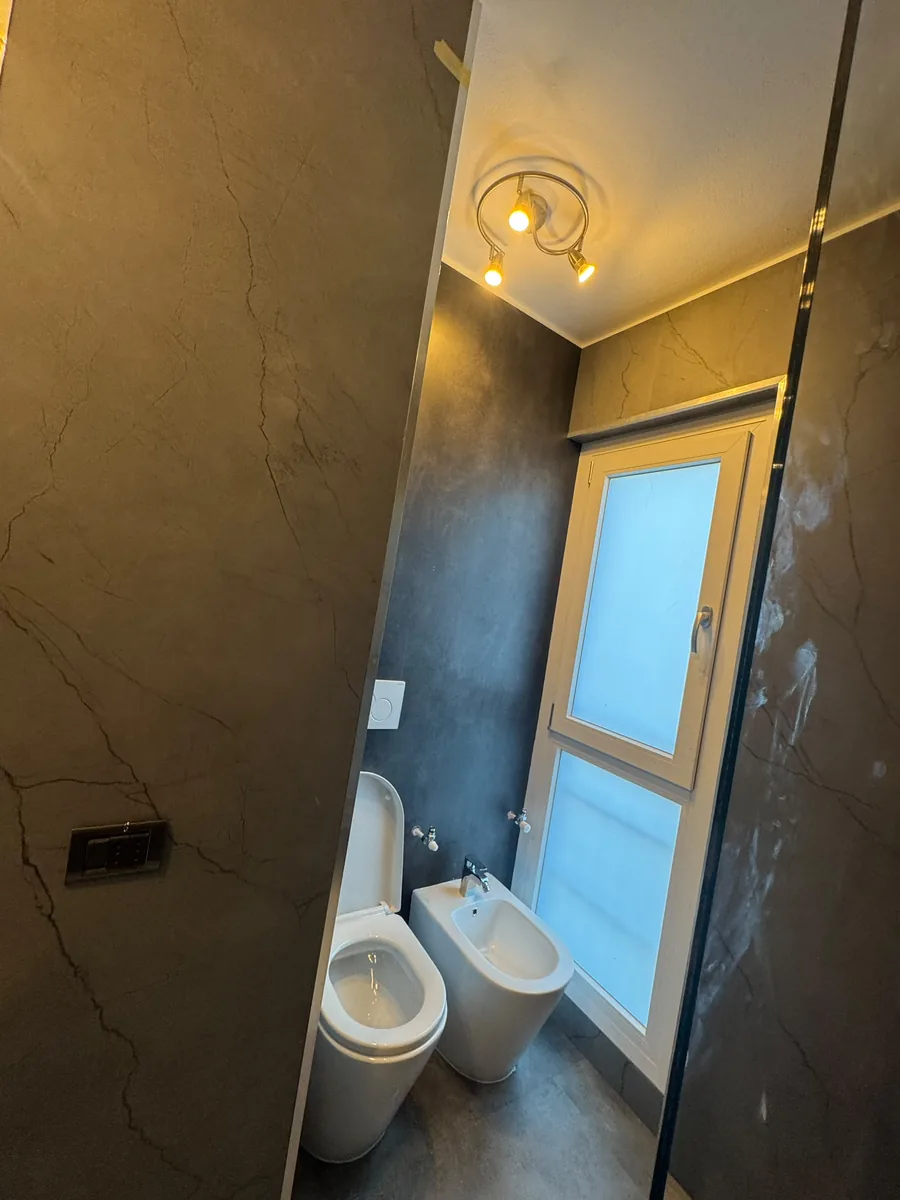 Bagno con rivestimento scuro e finestra a vetrocamera