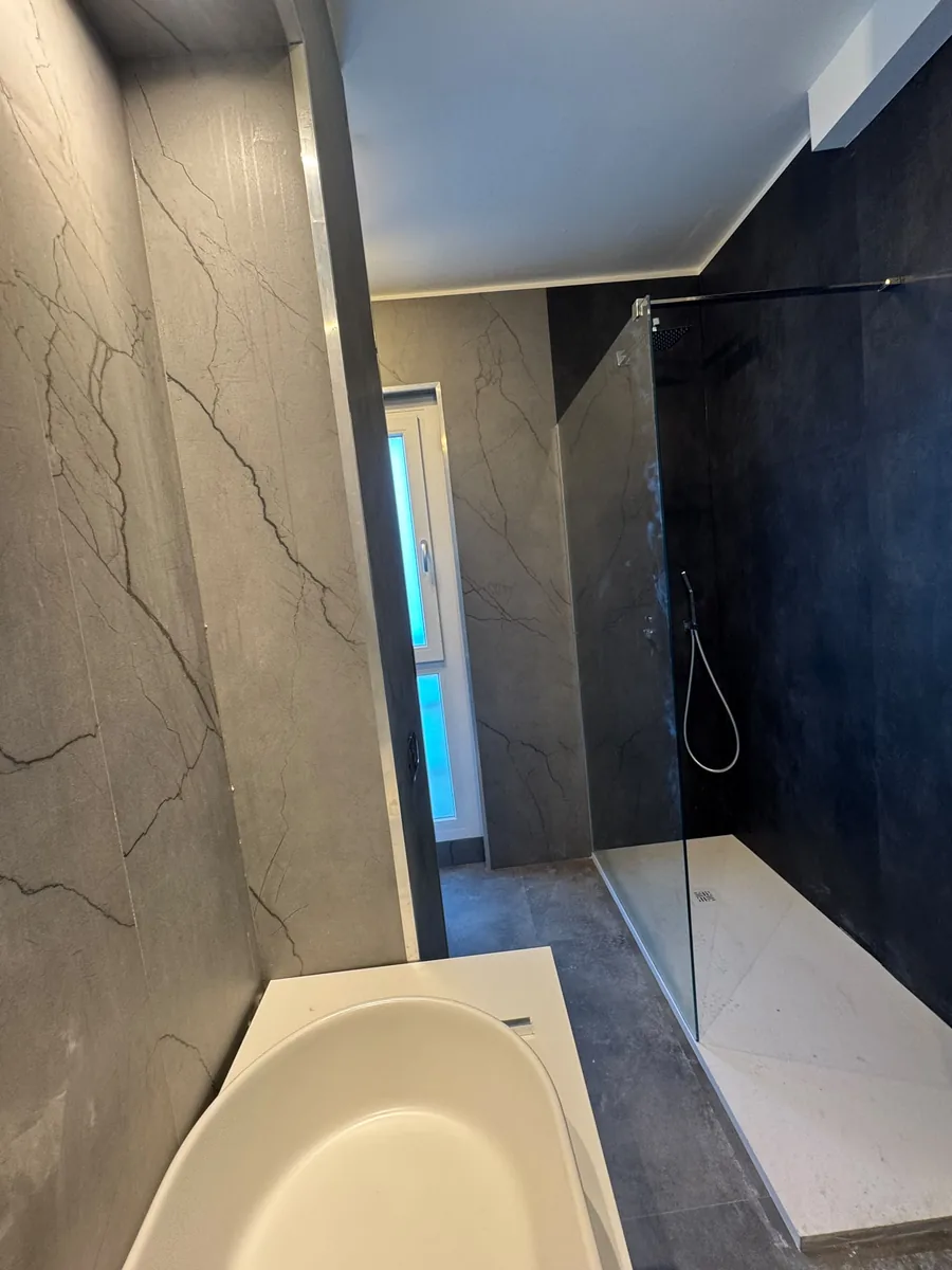 Vasca e doccia con rivestimento effetto marmo scuro